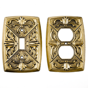 Vintage brass electrical plates with raised scrollwork designs and some patina