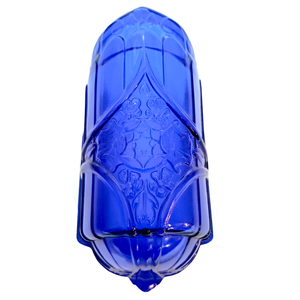 A cobalt blue glass slip shade with a rounded base and a pressed design in the middle mixing geometric and floral elements