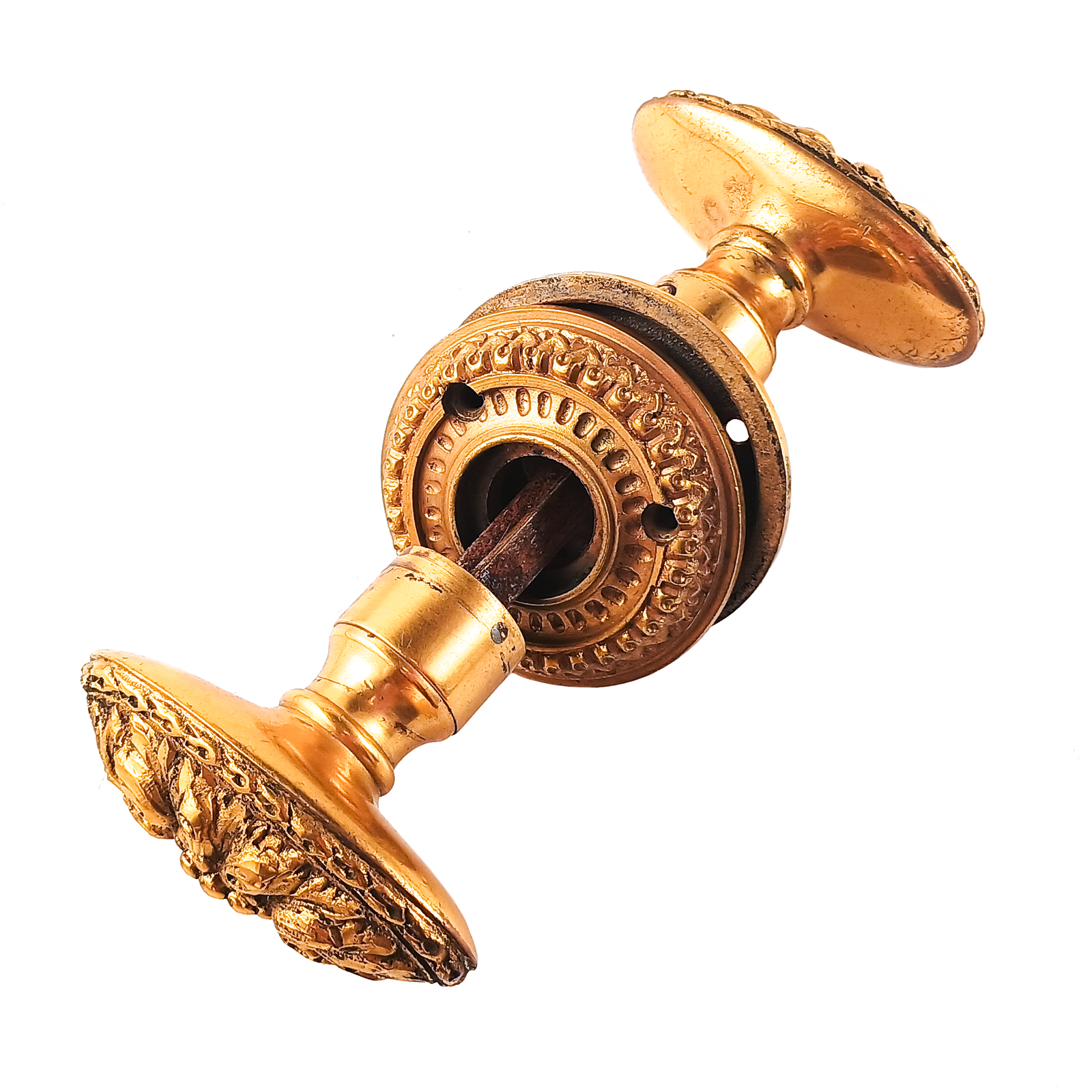 A set of two oval-shaped brass knobs with a floral design, along with two rosettes with a sort of frill design around the edges. The knobs and rosettes are all mounted on a spindle.