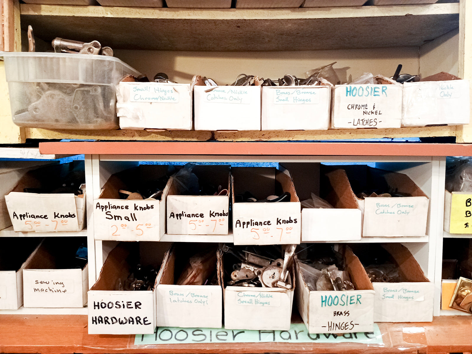 Several labeled boxes of Hoosier hardware and appliance knobs