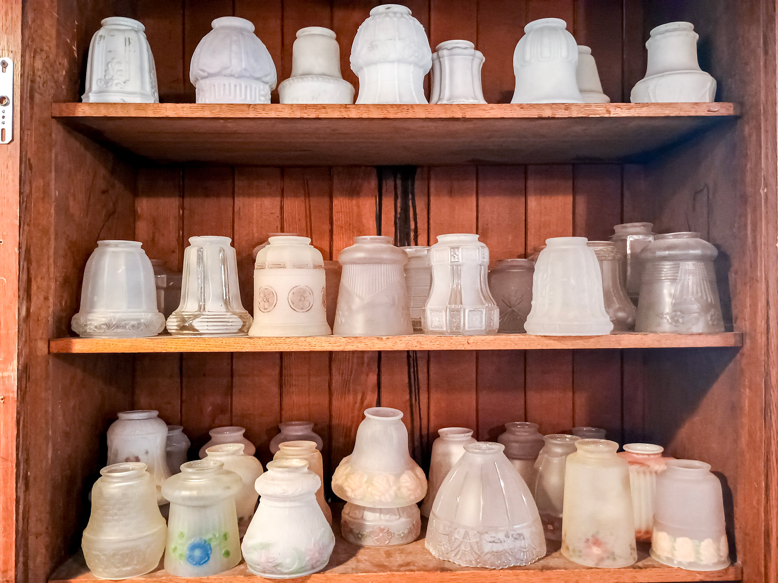 Three shelves of glass lamp shades