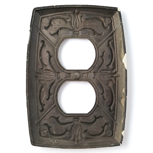 The back of the outlet plate, showing a small amount of off-white paint stuck to the edges