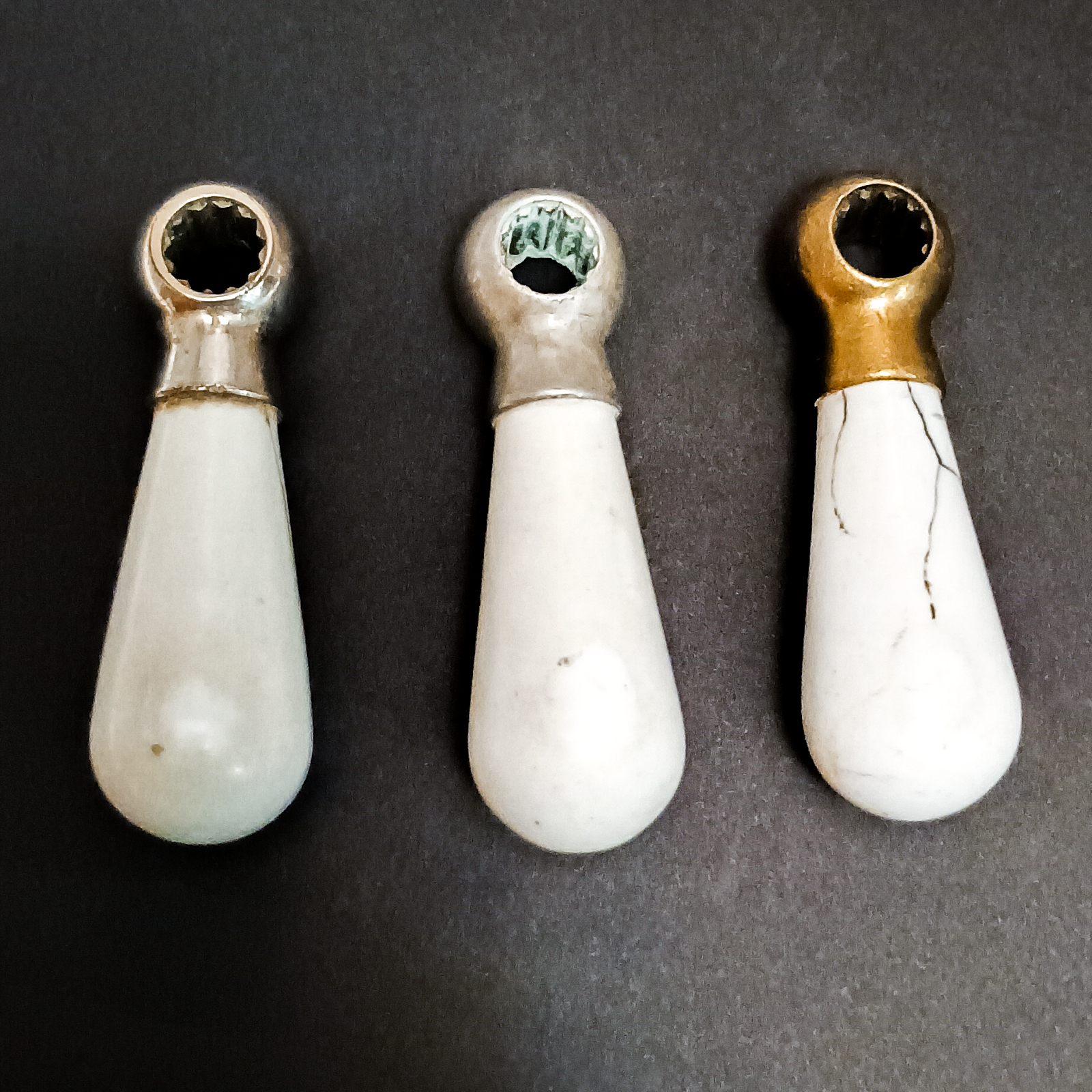 Three of the handles from the previous photo. One cold with a small visible crack and some of the nickel finish coming off, one cold with no damage except some verdigris and limescale inside the top, and one hot with significant cracks, scratches, and no visible nickel plate remaining