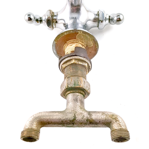 The bottom half of an antique chrome-plated mixer faucet, showing moderate wear