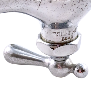 A close-up of the "Standard" RE-NU stamp on an antique mixer faucet