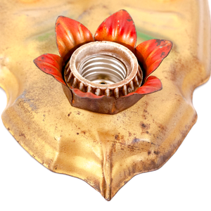 A close-up of a light socket in a vintage gold-tone fixture. The socket is surrounded by metal flower petals which have been painted red.