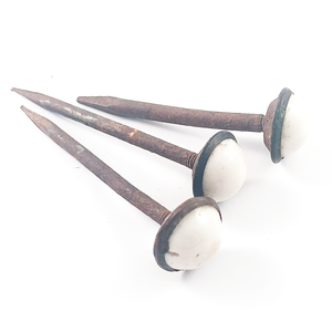 Three rusted iron nails with domed white ceramic heads in dark iron settings