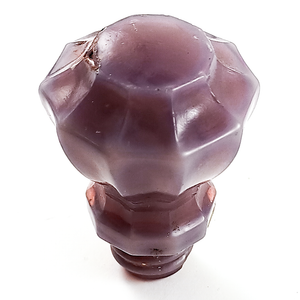 A fluted knob made entirely of light, greyish/pinkish purple glass. It has some slight dings and chips in the surface.