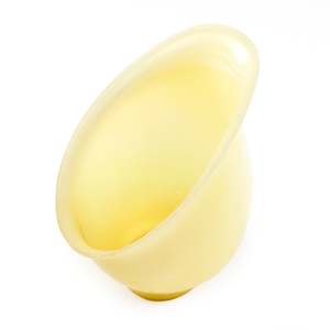 A greenish-yellow off-white lamp shade. The shade is an asymmetrical bell shape, with a heavily slanted opening almost as if you sliced diagonally into a standard bell shade, and has a curved lip around the opening.