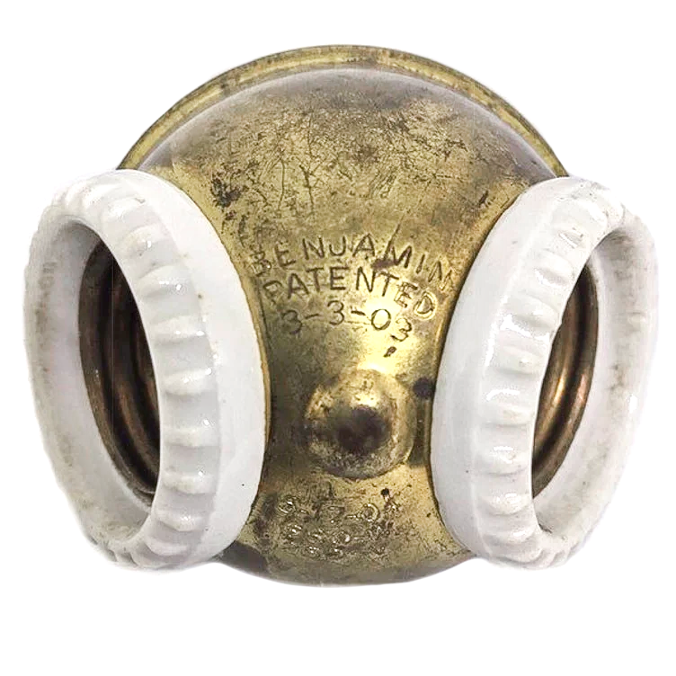 An antique brass two-socket Benjamin cluster with porcelain rings around the sockets and a patent stamp from 1903