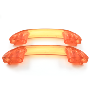 Two bright orange translucent Bakelite drawer handles, with darker orange sections at each end. Yellow patches of light on the background show the way light shines through them.