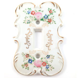 A white porcelain single-gang light switch plate, with floral motifs and gilded scrolling designs
