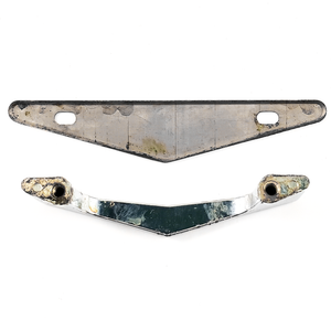 The backs of a chevron-shaped chrome-plated drawer handle and its triangular back plate, both of which show some wear
