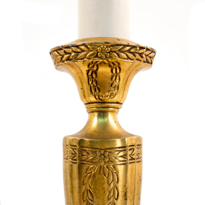 A close-up of floral detailing on an Art Nouveau brass table lamp shaped like a candlestick
