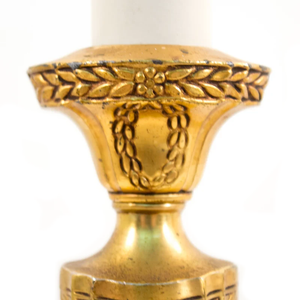 A close-up of floral detailing on an Art Nouveau brass table lamp shaped like a candlestick