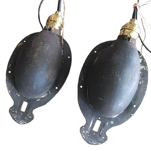 The backs of two antique curved oval iron wall sconces, showing a capital "C" stamped into the back of each sconce