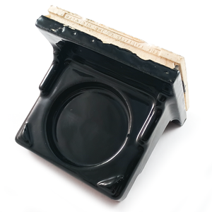 A porcelain tile-in cup holder glazed in glossy black, with triangles at the two outer corners. The portion that tiles in is stamped, reading "THE FAIRFACTS CO INC NEW YORK"