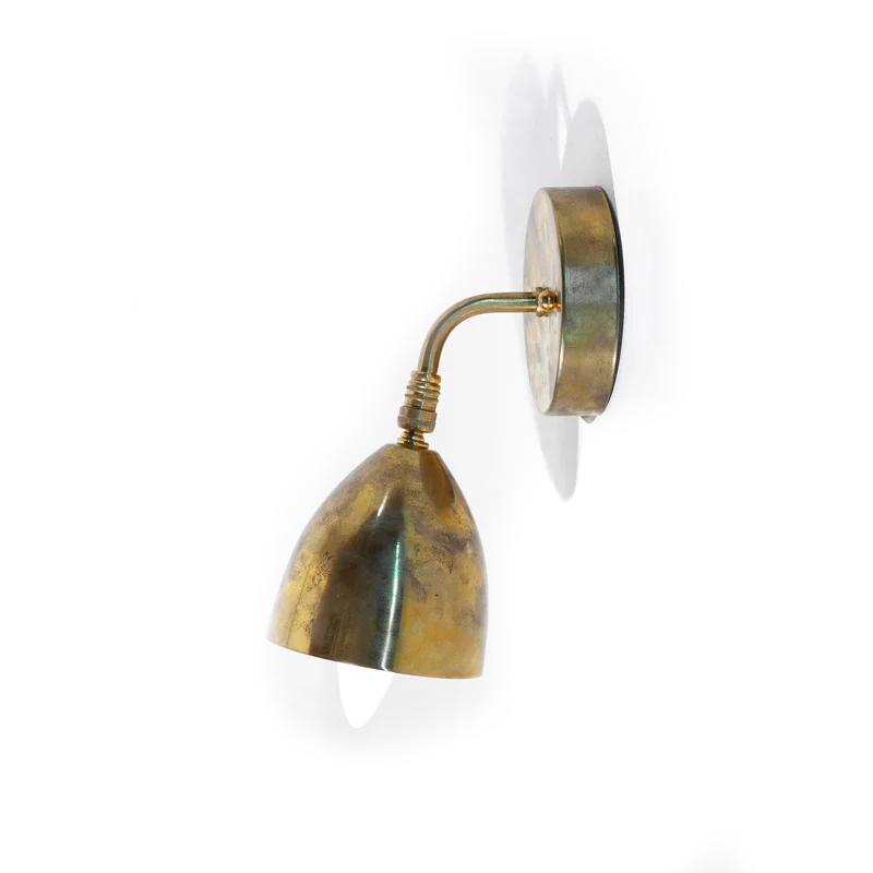 A vintage brass wall sconce shown from the side, with a bell-shaped shade and a bulb installed for display