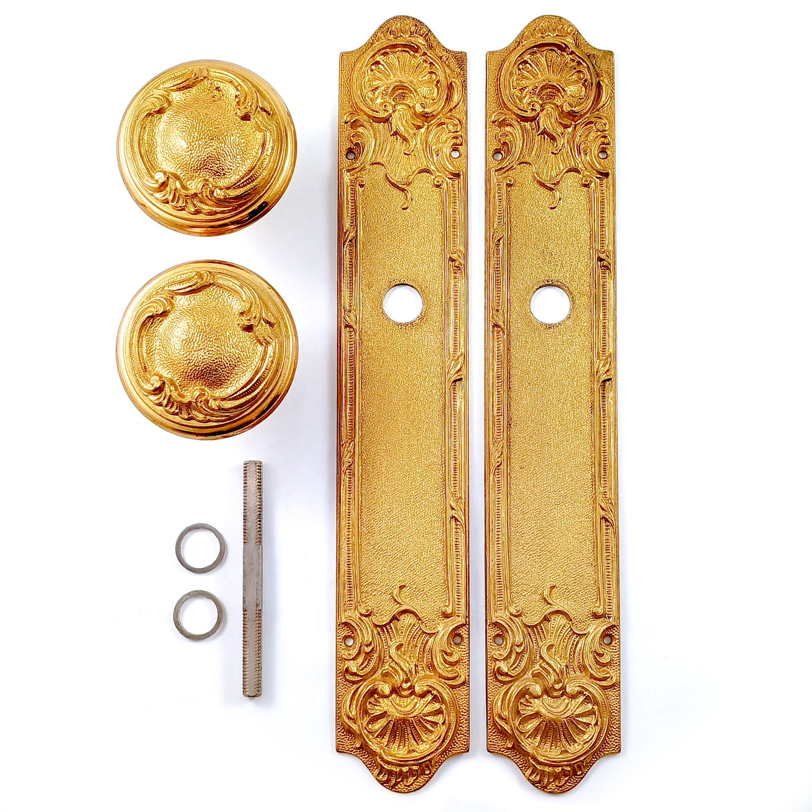 A vintage brass doorknob and escutcheon set, decorated in an Art Nouveau revivalist style with ornate scrolling details