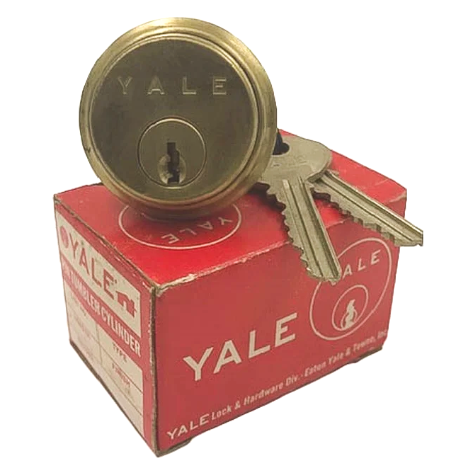 A vintage brass Yale cylinder lock on top of its red original box, alongside a pair of keys