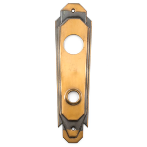 A bronze Art Deco escutcheon with areas of dark patina and two round holes, one for a cylinder lock and one for a doorknob