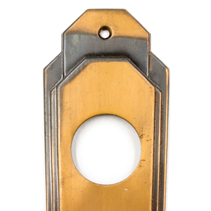 A close-up of the cylinder hole of a bronze Art Deco escutcheon