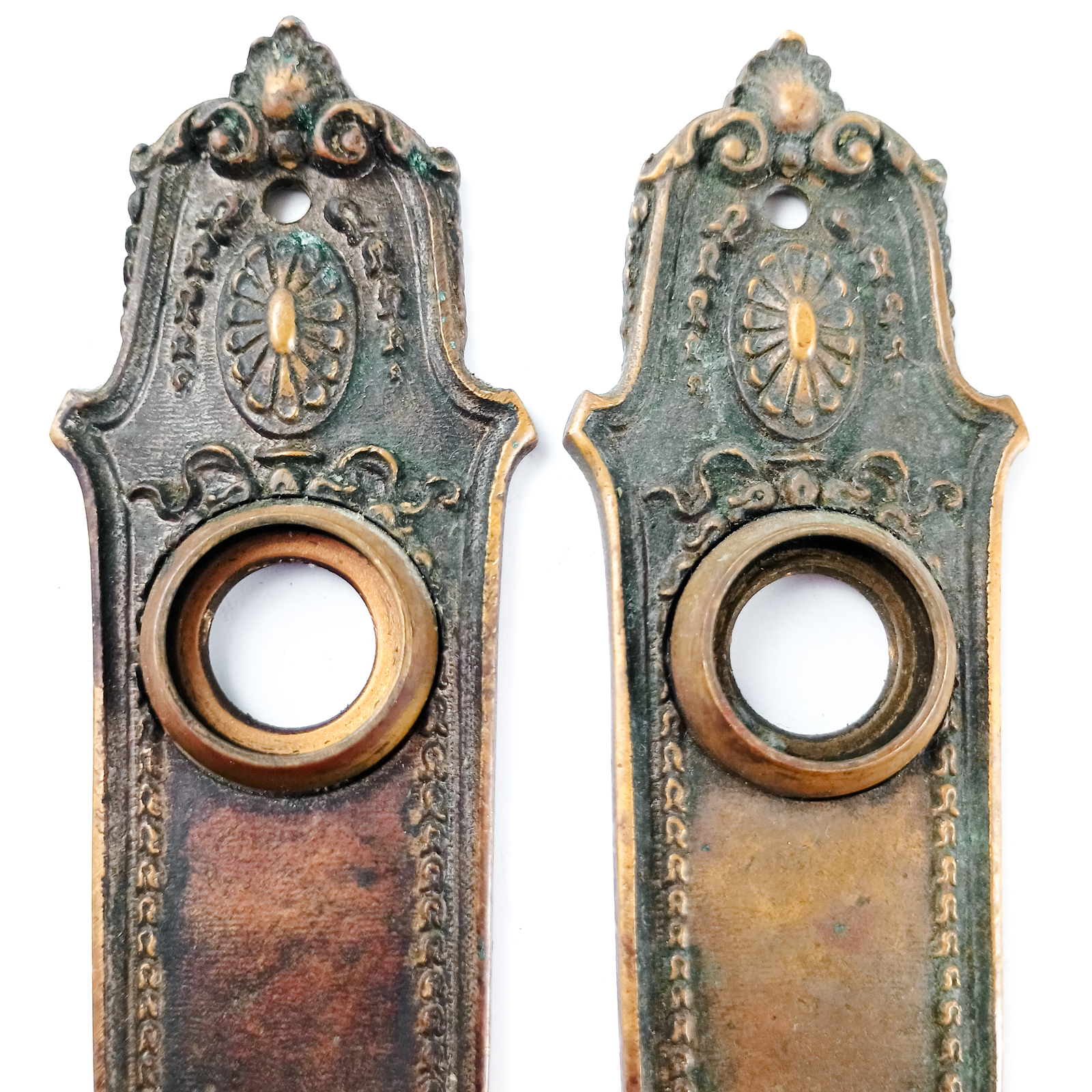 Two bronze escutcheons shaped like saggers with scrolling, somewhat floral decorations