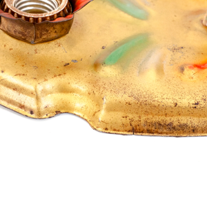 A close-up of the edge of a vintage gold-tone ceiling light fixture, showing some of the surface wear