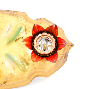 A close-up of a light socket in a vintage gold-tone fixture. The socket is surrounded by metal flower petals which have been painted red.