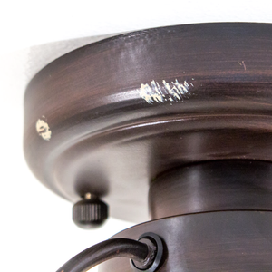 A close-up of the base of a ceiling-mounted lighting fixture, which has a small amount of off-white paint on it