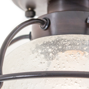 A close-up of the bubbly glass shade and dark bronze-finished metal accents of an industrial ceiling-mount lighting fixture