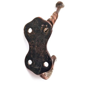 The back of an iron coat hook with copper finished areas, showing four screw holes as well.