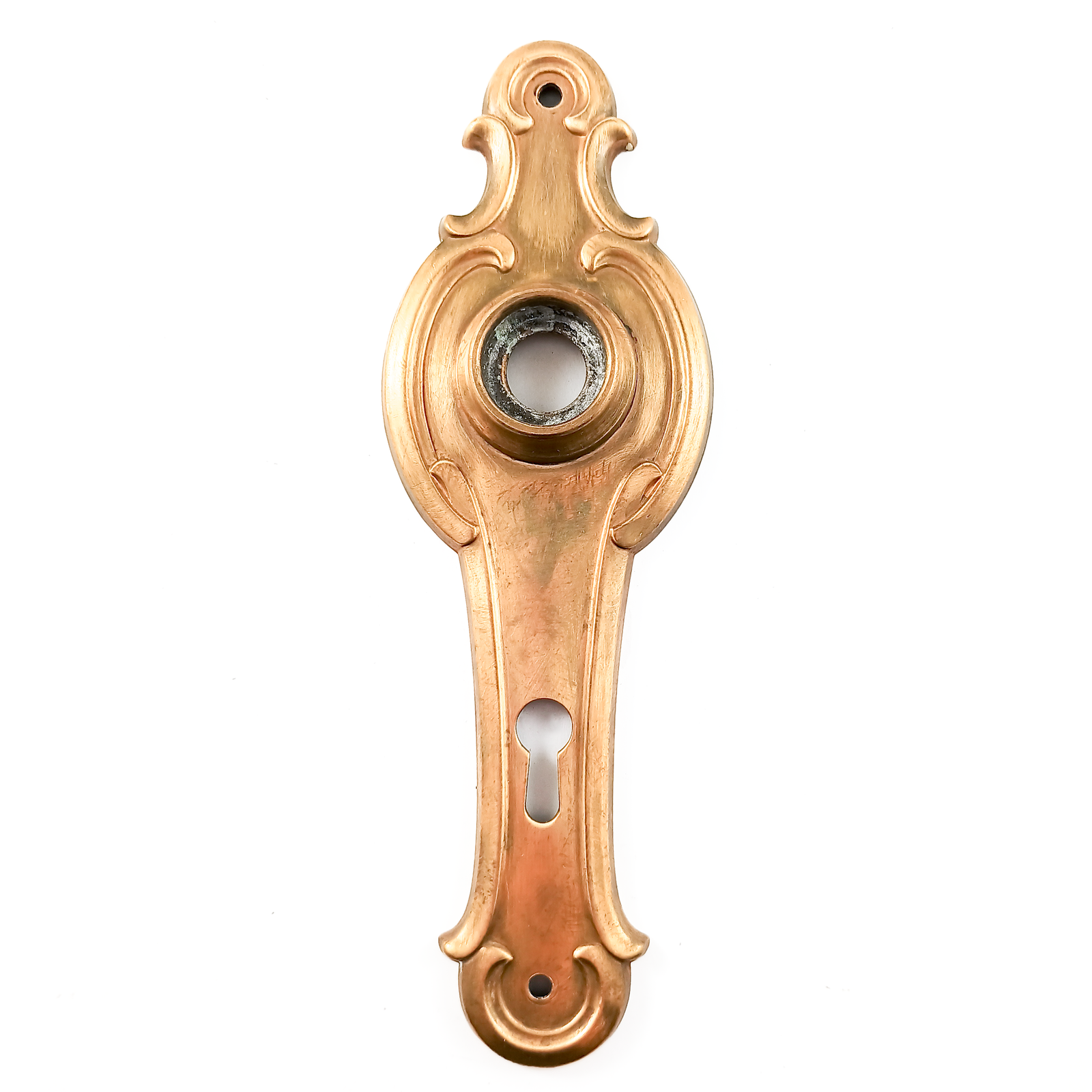 A vintage brass escutcheon, with an opening for a doorknob and a keyhole. The brass is lightly scratched in some places, and there is visible verdigris inside the bezel. The whole piece is designed in curving, symmetrical shapes.