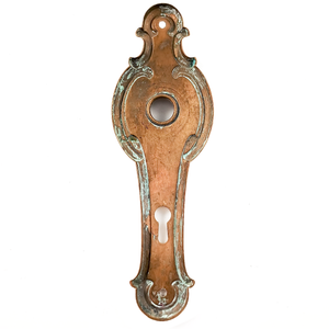 The back of a vintage brass escutcheon, showing a fair amount of verdigris and significant patina.
