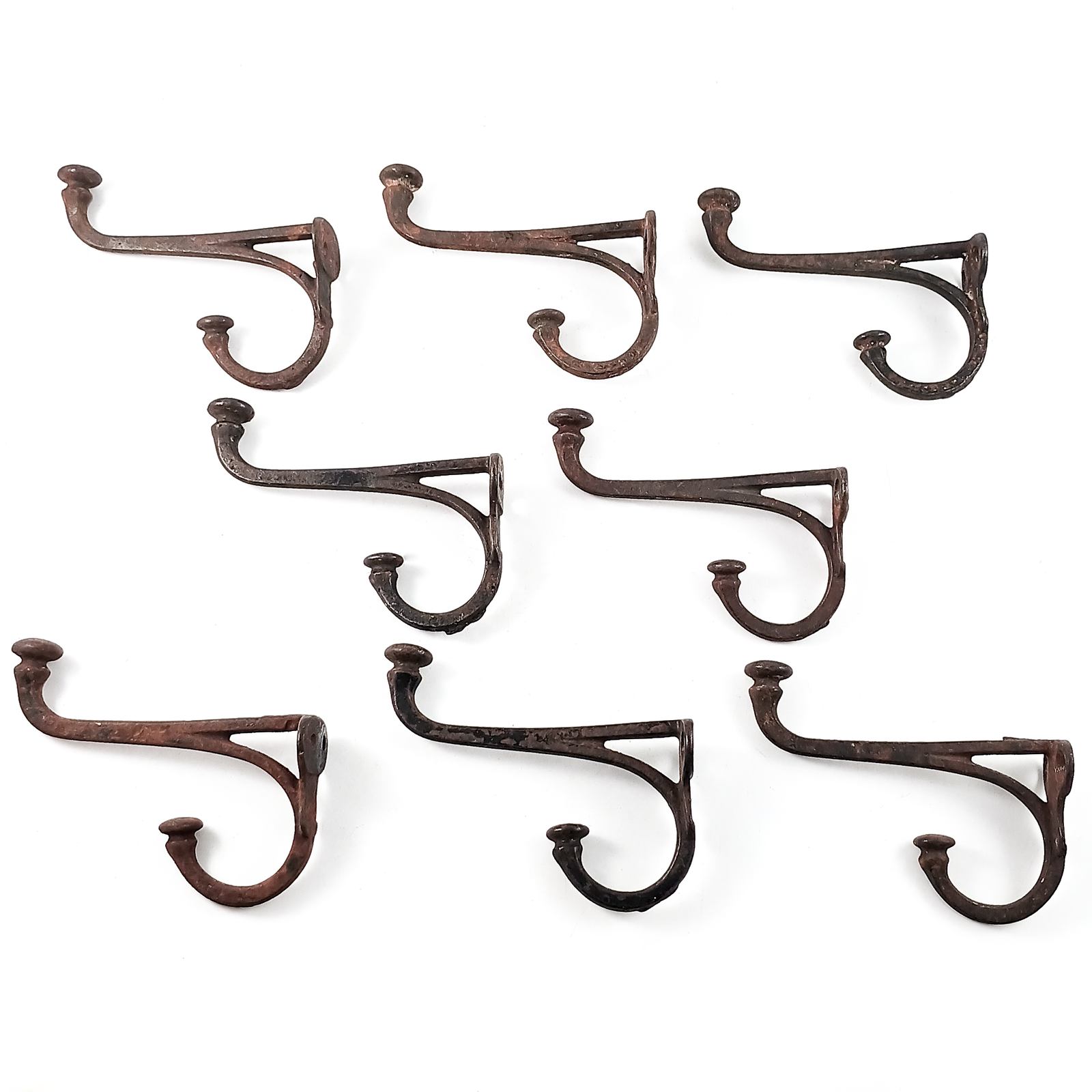 A cast iron double coat hook with acorn ends, some surface rust, and some remaining black enamel coating