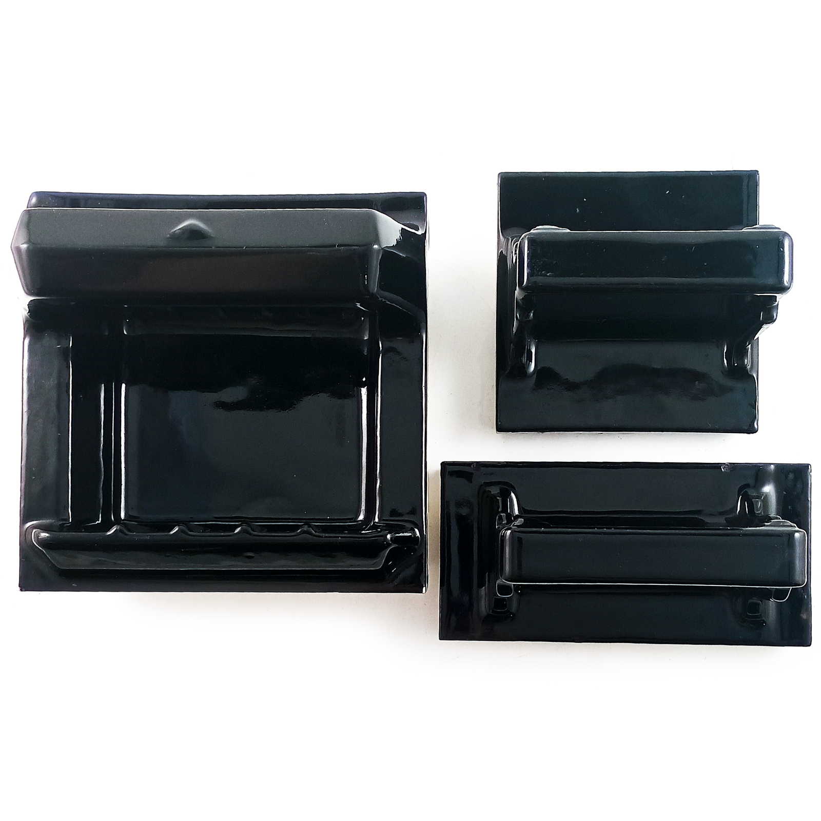 A set of three tile-in porcelain bathroom accessories, glazed in black - a soap dish with a bar above it, a cup holder, and a toothbrush holder with cup holder