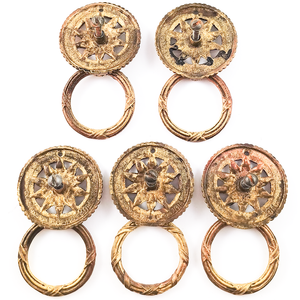 The backs of five vintage brass ring pulls, showing the decorated rings, plain backs, and slotted mounting screws sticking out of the back of each pull.