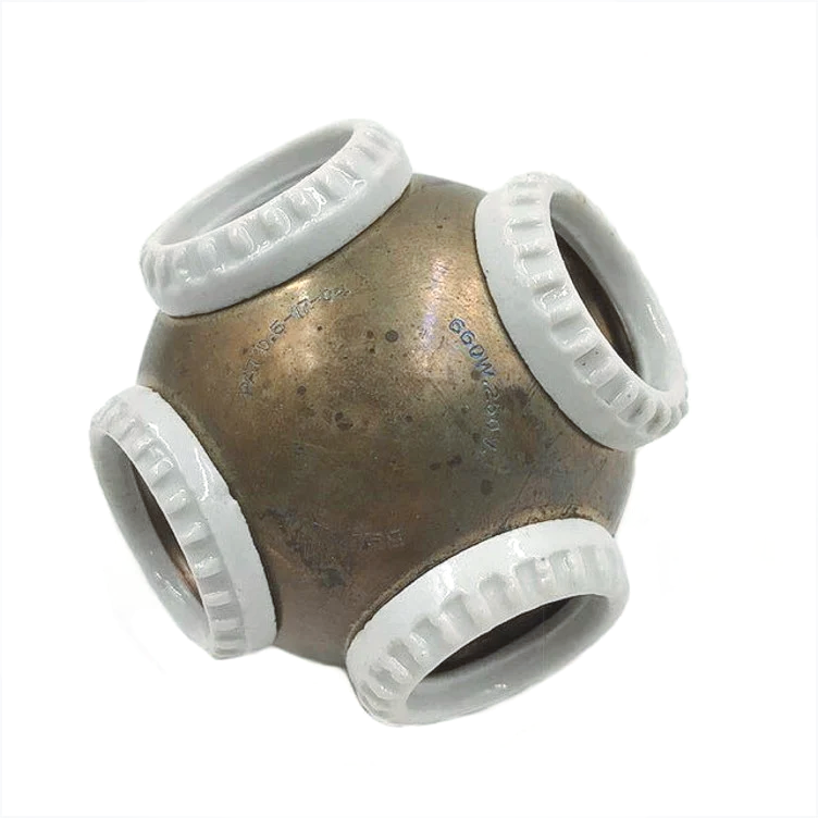A brass ball with four white ceramic rings on it, each surrounding a light socket