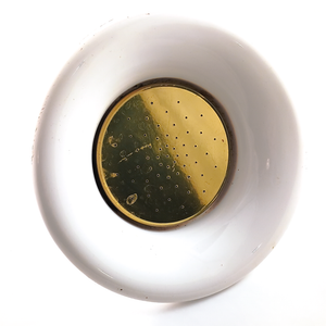 A round brass showerhead with a white porcelain surround. The brass has some visible water drop staining, and the porcelain has some small stains and divots.