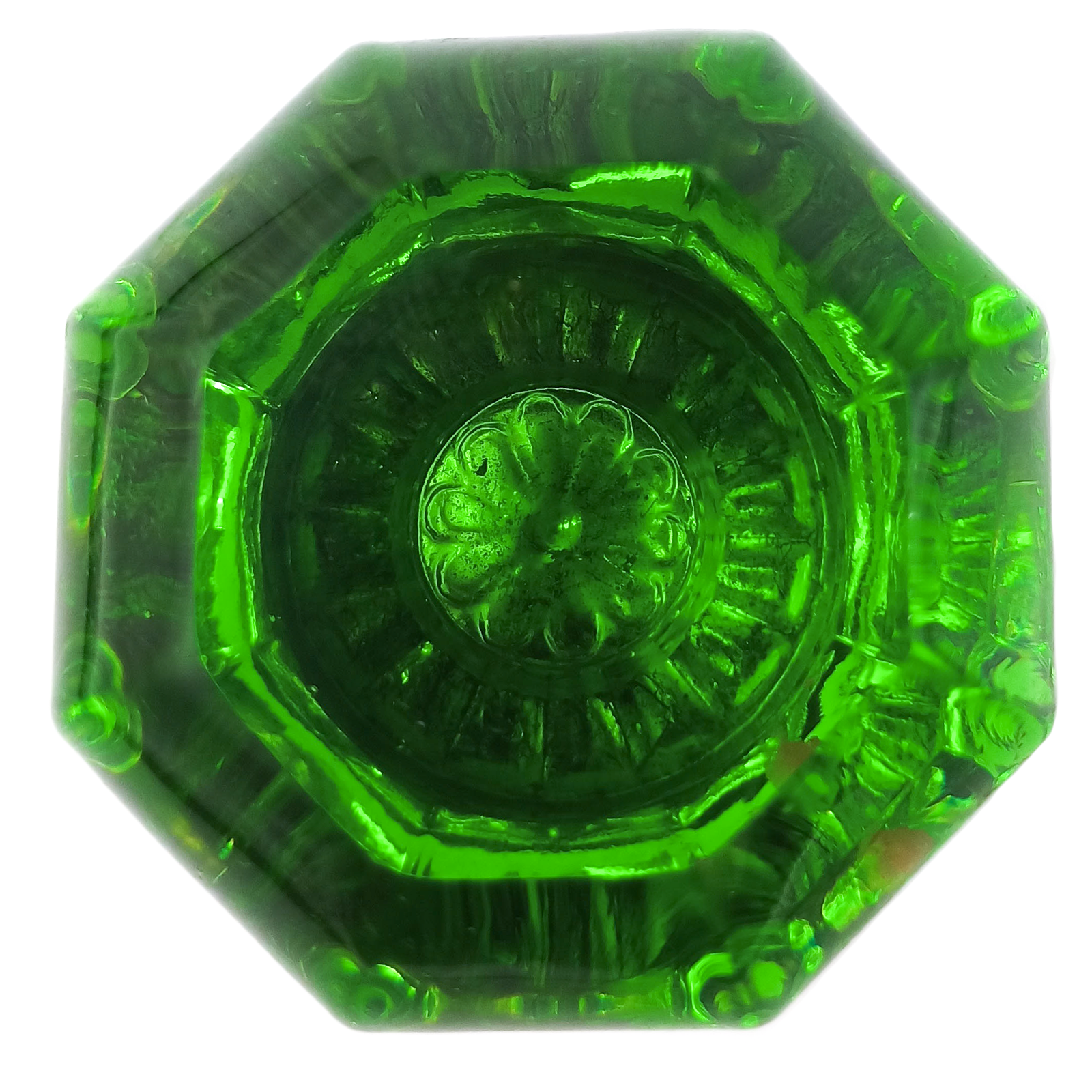A head-on photo of an antique, octagonal, green glass doorknob with a floral design in the center