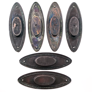 Six oval pocket door pulls with beaded trim, shown from the back. The backs are all coated with a dark finish, though some are more even than others. Four pulls have key holes, two do not.