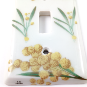 A close-up of the bottom edge of one of the yellow flower light switch plates, showing the "J.M LIMOGES" stamp more clearly. The close-up also makes it clear that the yellow flowers are a print transfer.