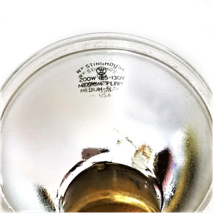 The stamp on the back of a Westinghouse par lamp, featuring the company name and logo, as well as stating "200W 125-130V MEDIUM FLOOD USA"