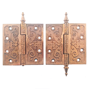 Two pairs of ornate brass hinges, one of which is missing a finial. The brass finish shows very little wear or patina.
