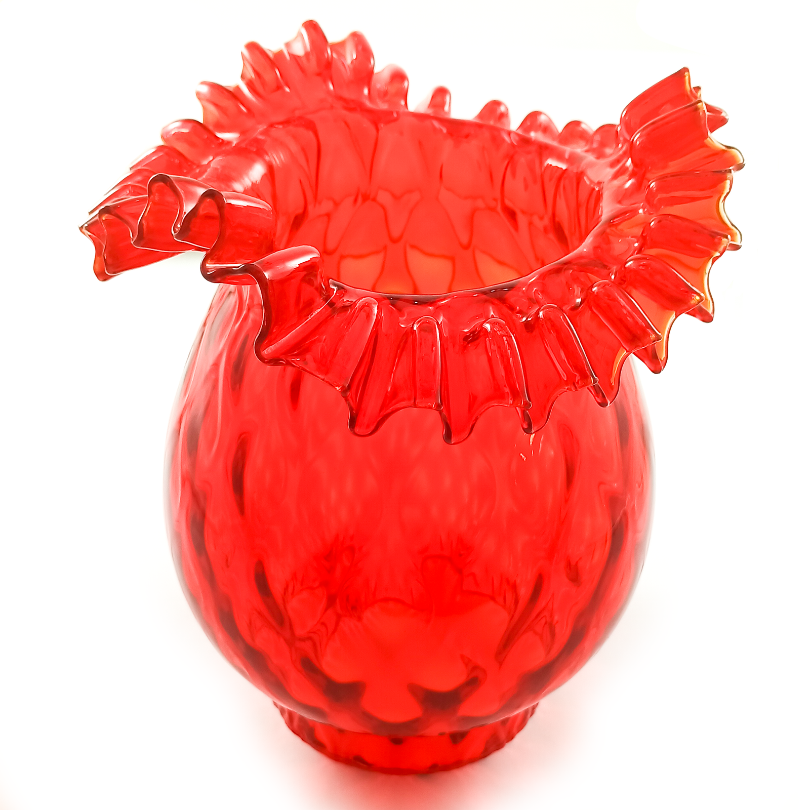 A red bell-shaped lamp shade with a hand-crimped ruffled edge and a textured body, sitting on its fitter