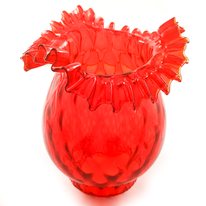 A red bell-shaped lamp shade with a hand-crimped ruffled edge and a textured body, sitting on its fitter
