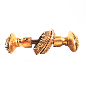 A view of both knobs and rosettes from the side. There is some surface wear and patina visible on the base of each knob, and one of the set screws is shown.