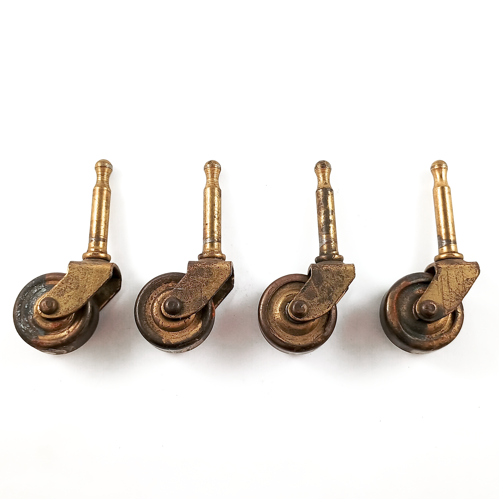 Four antique grip-neck stem casters in a line, with brass hardware and wheels. They show significant surface wear.