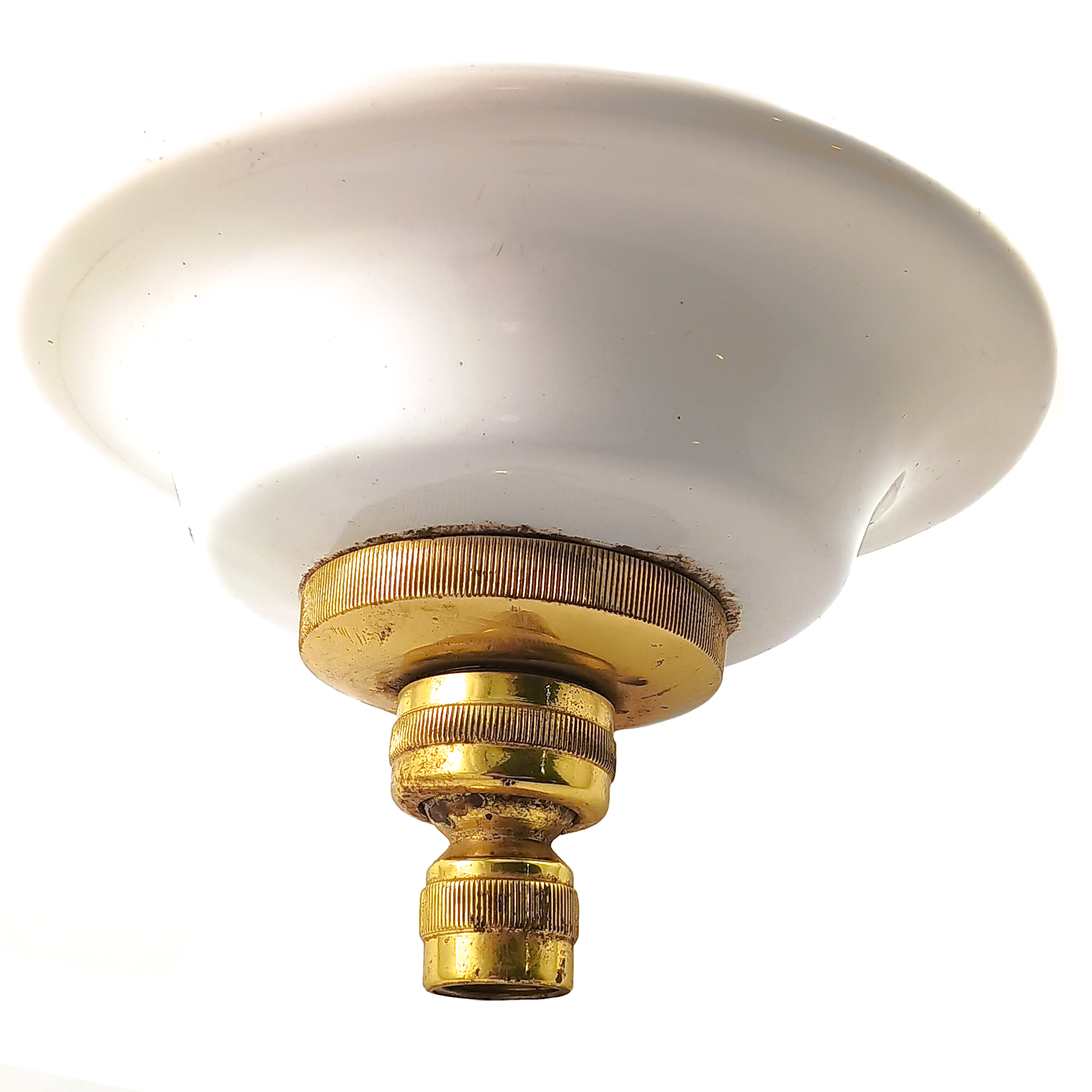 A round brass showerhead with a white porcelain surround. The brass has some visible water drop staining, and the porcelain has some small stains and divots.