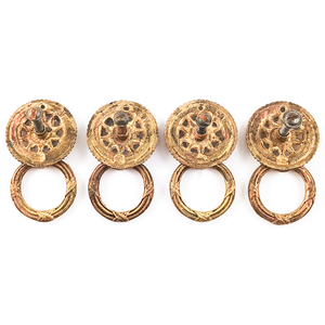 The backs of four vintage brass rings pulls, showing the decorated rings in contrast to the plain backs, and showing slotted mounting screws in each pull.